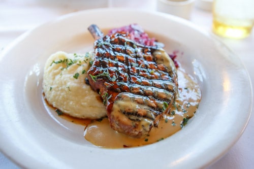 Mustards Grill signature dishes Mongolian Pork Chop, Famous Onion Rings, Wood-Fired Pizzas, Lemon-Lime Tart.